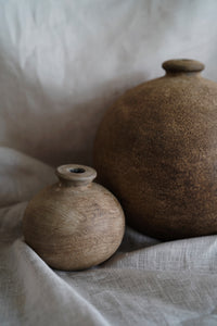 A hand thrown clay vessel with an organic textured finish. Paired here with the large mud vase
